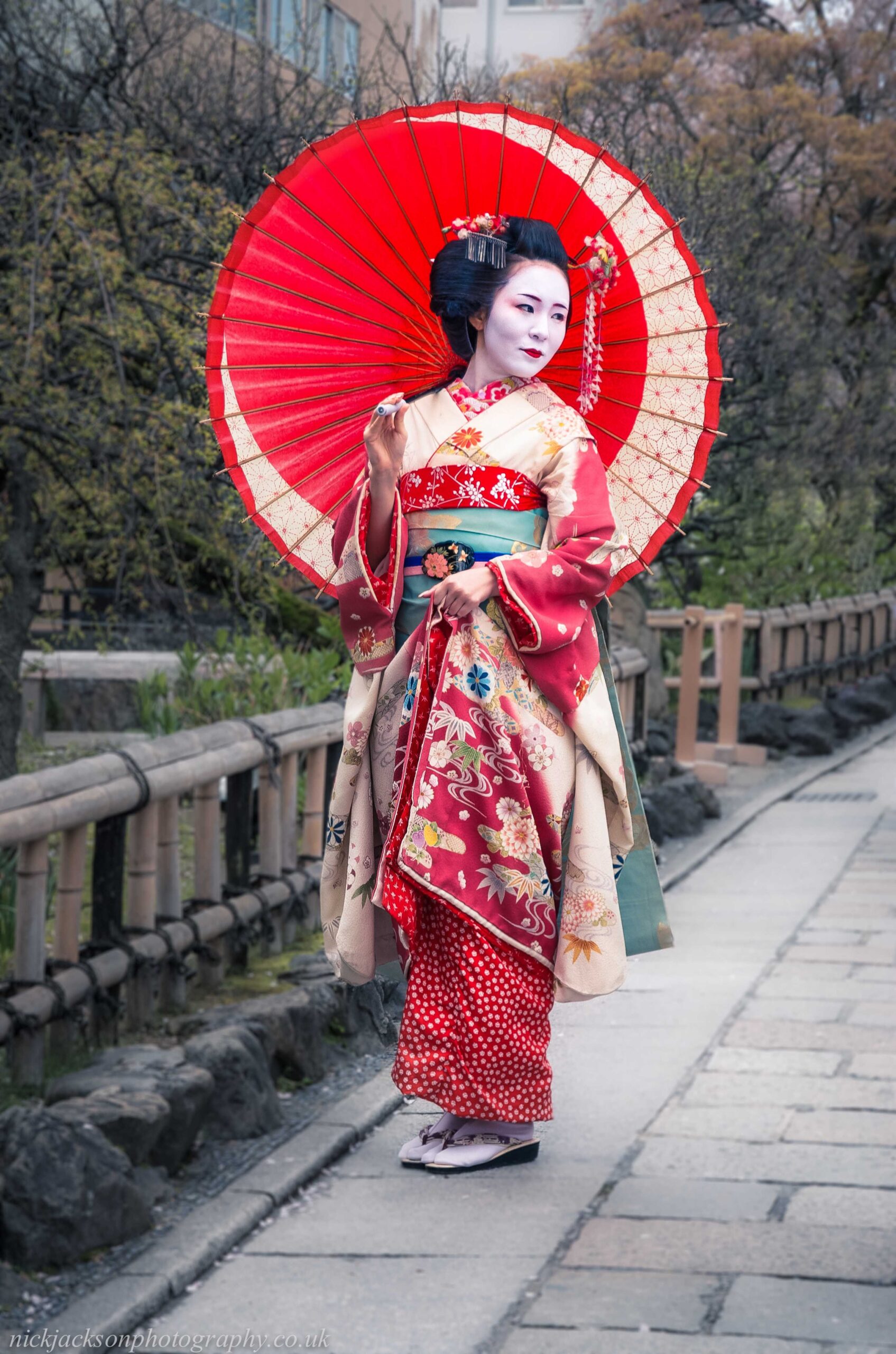 Japanese geisha wearing a traditional kimono walking along the historic streets of Gion in Kyoto, Japan.